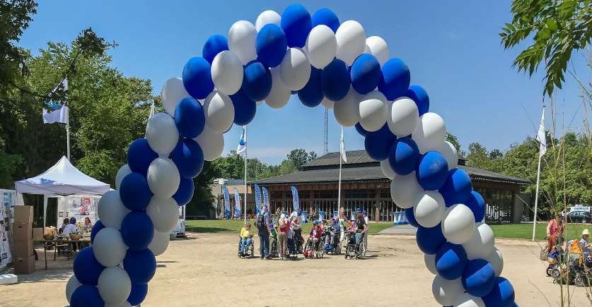Gasten in rolstoel onder de ballonnenboog aan de ingang van Planckendael